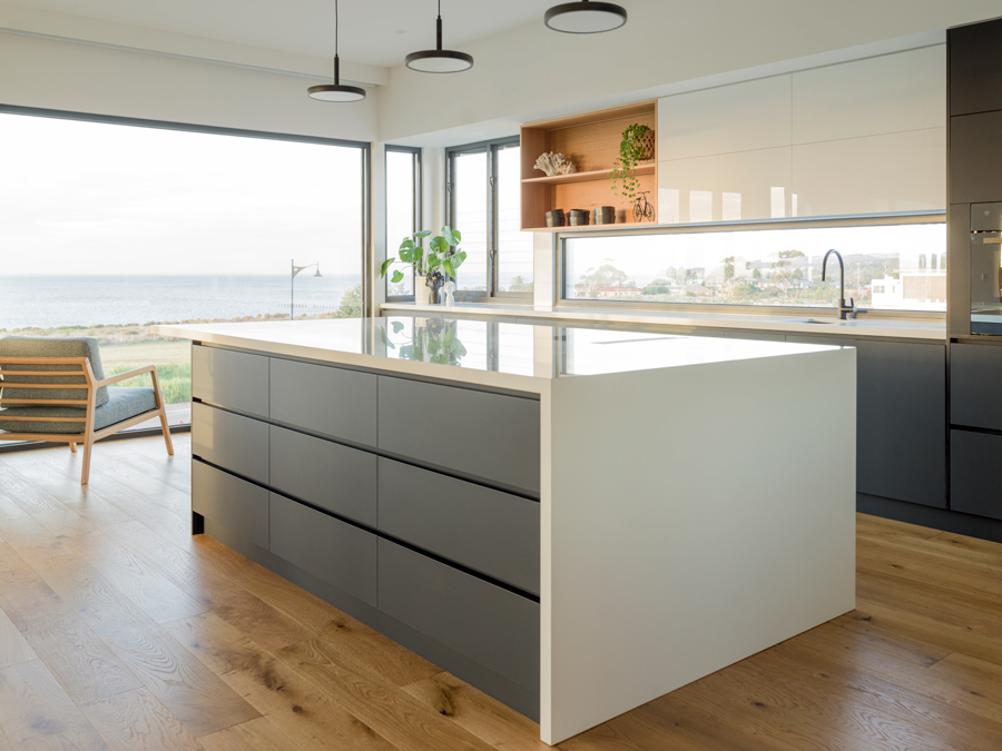 Open plan kitchen with large island stone benchtop with full length waterfall edge