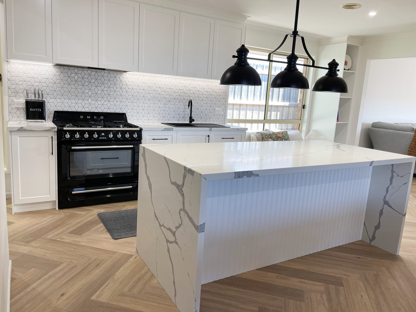 White Stone Kitchen Benchtop with black hanging lights and modern black oven