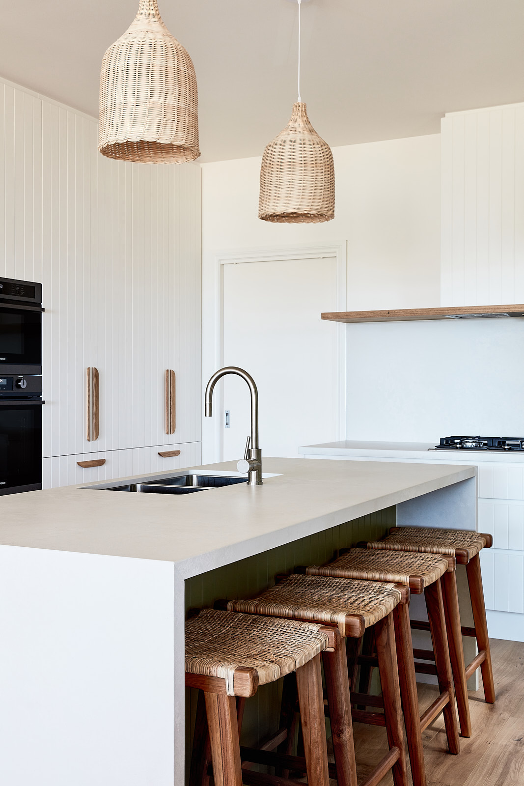 Image of a tidy kitchen with hanging lights and stone benchtop.